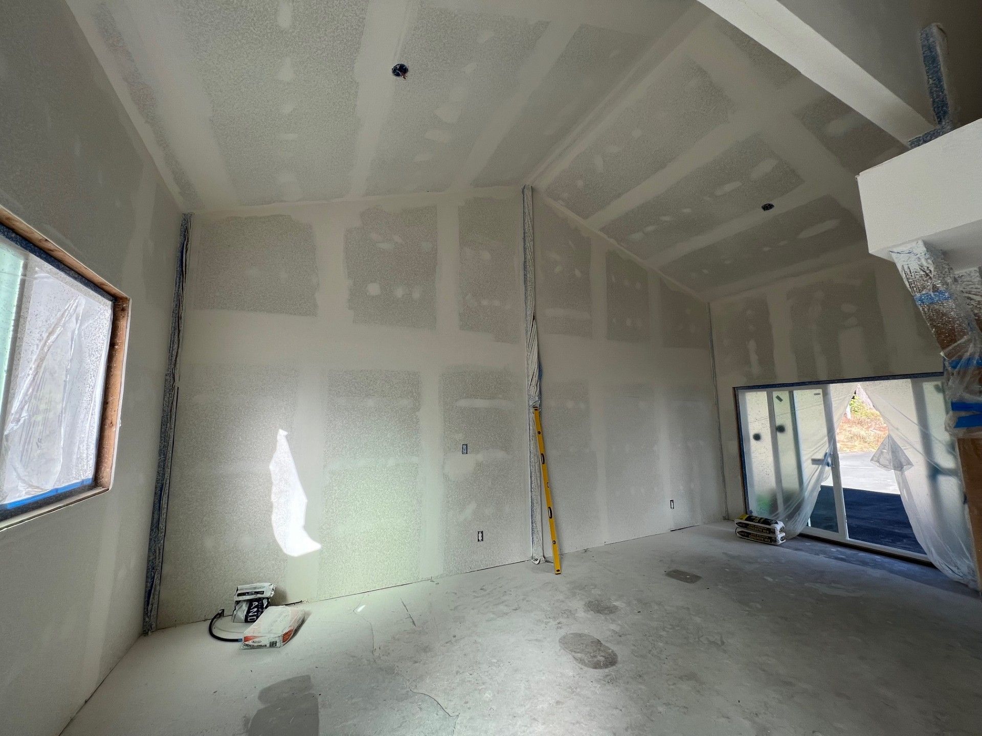 Interior under construction; drywall on walls and ceiling, exposed framing, tools present.