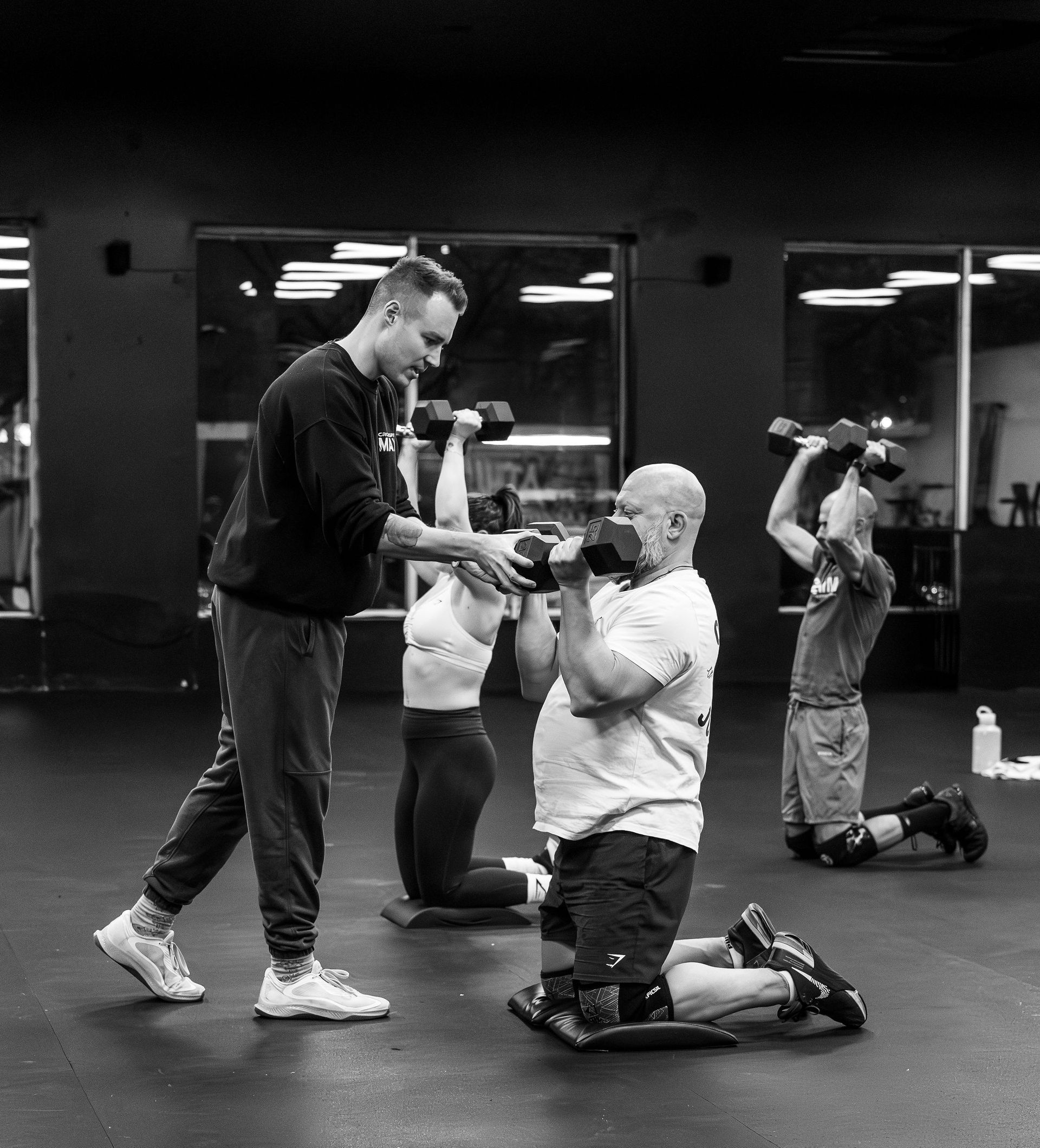 Un groupe de personnes soulève des haltères dans une salle de sport.