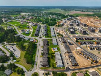Blue dumpster on a construction site with a partially framed house in the background.