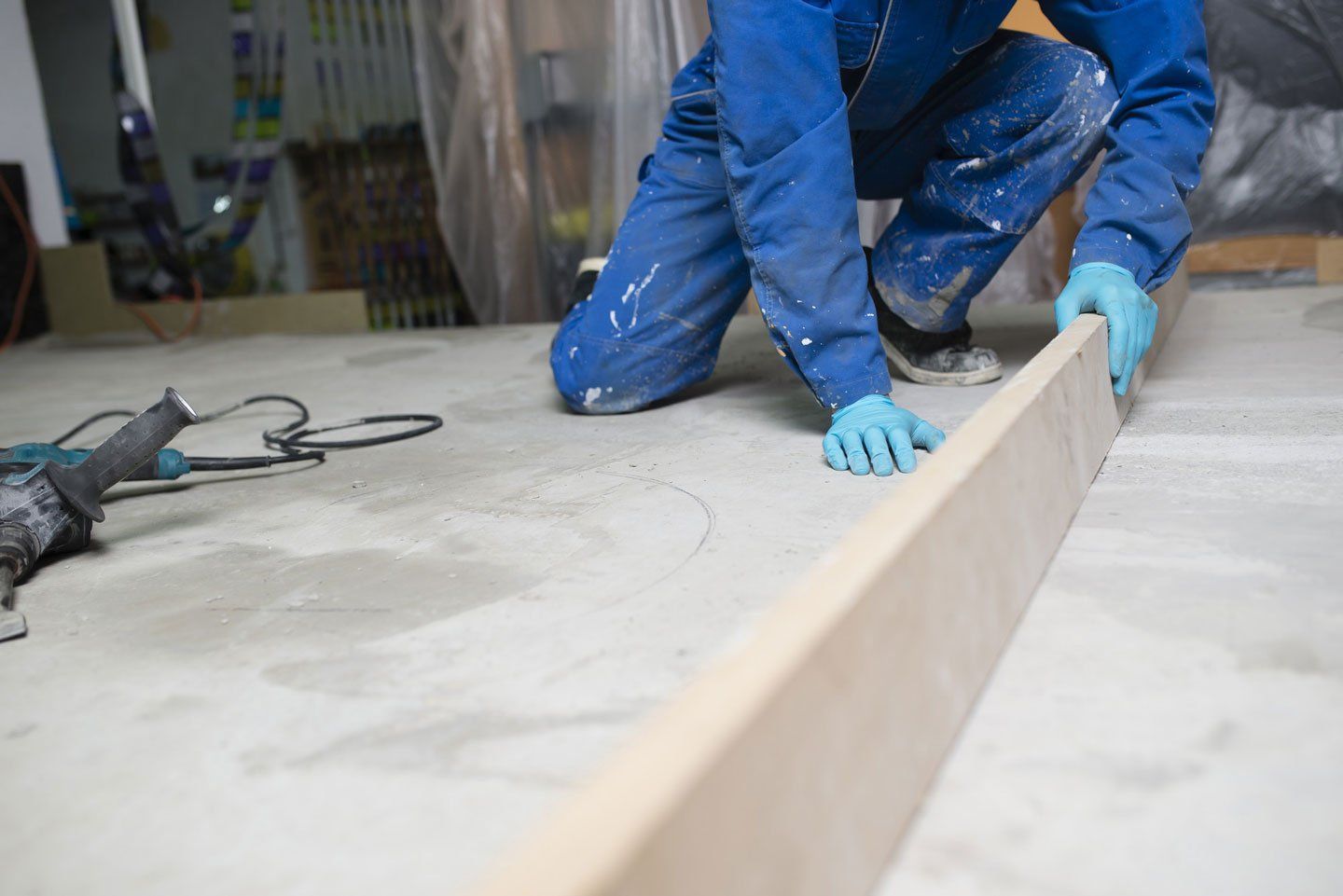 An expert in uniform is holding up a wooden plank horizontally for screeding