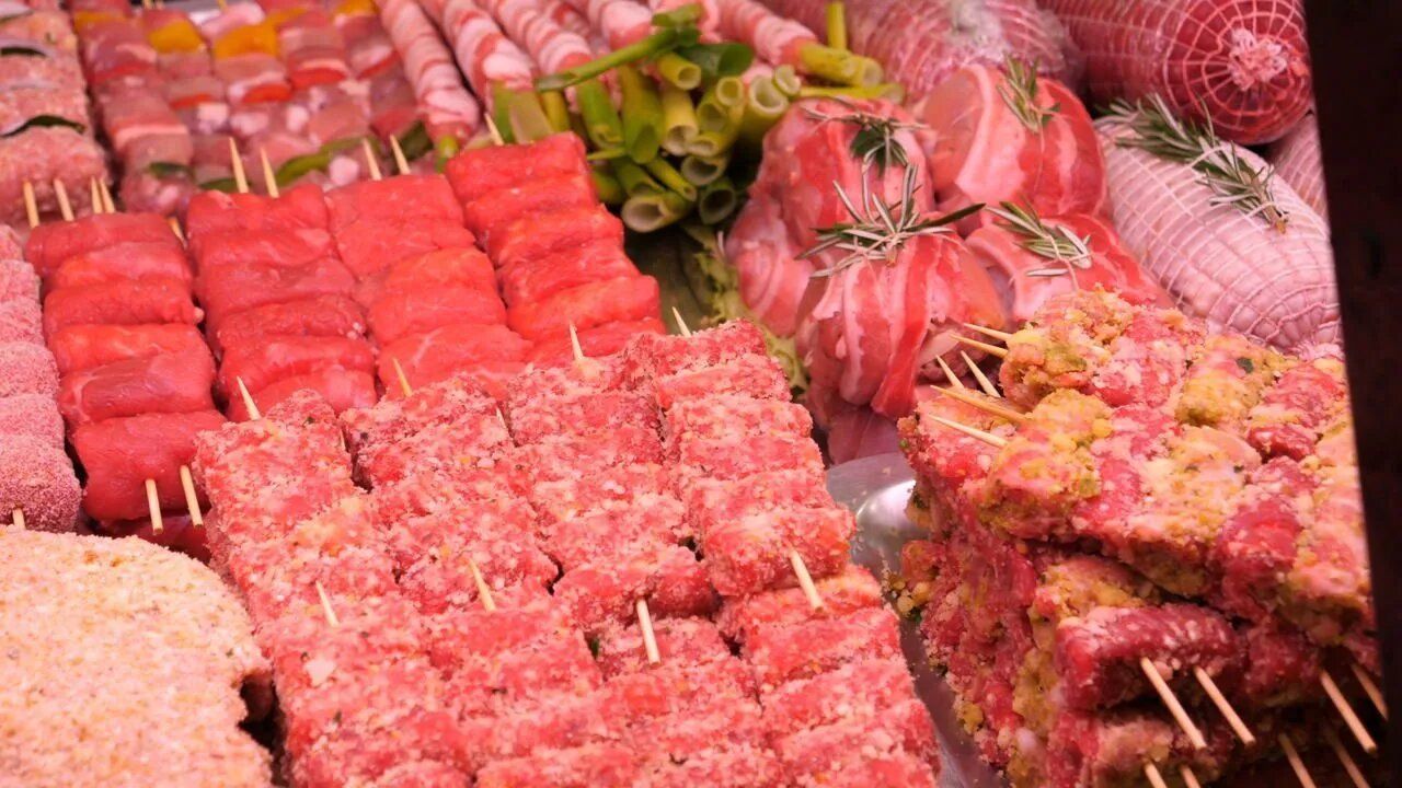 Vetrina con vari tipi di carne cruda, tra cui spiedini e tagli incartati.