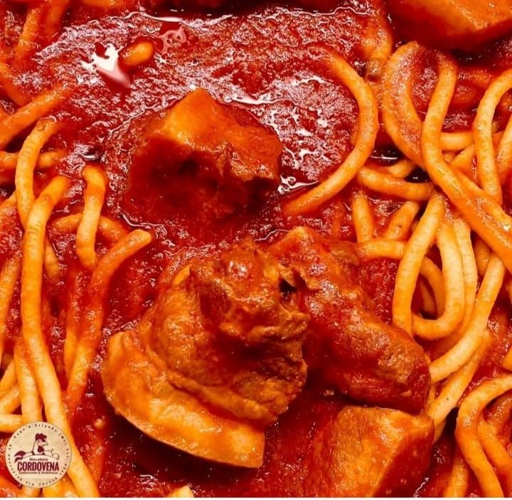 Spaghetti al sugo rosso e pezzi di carne in primo piano.