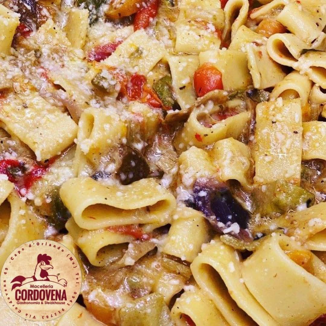 Pasta con verdure, tra cui melanzane e pomodori, cosparsa di formaggio.