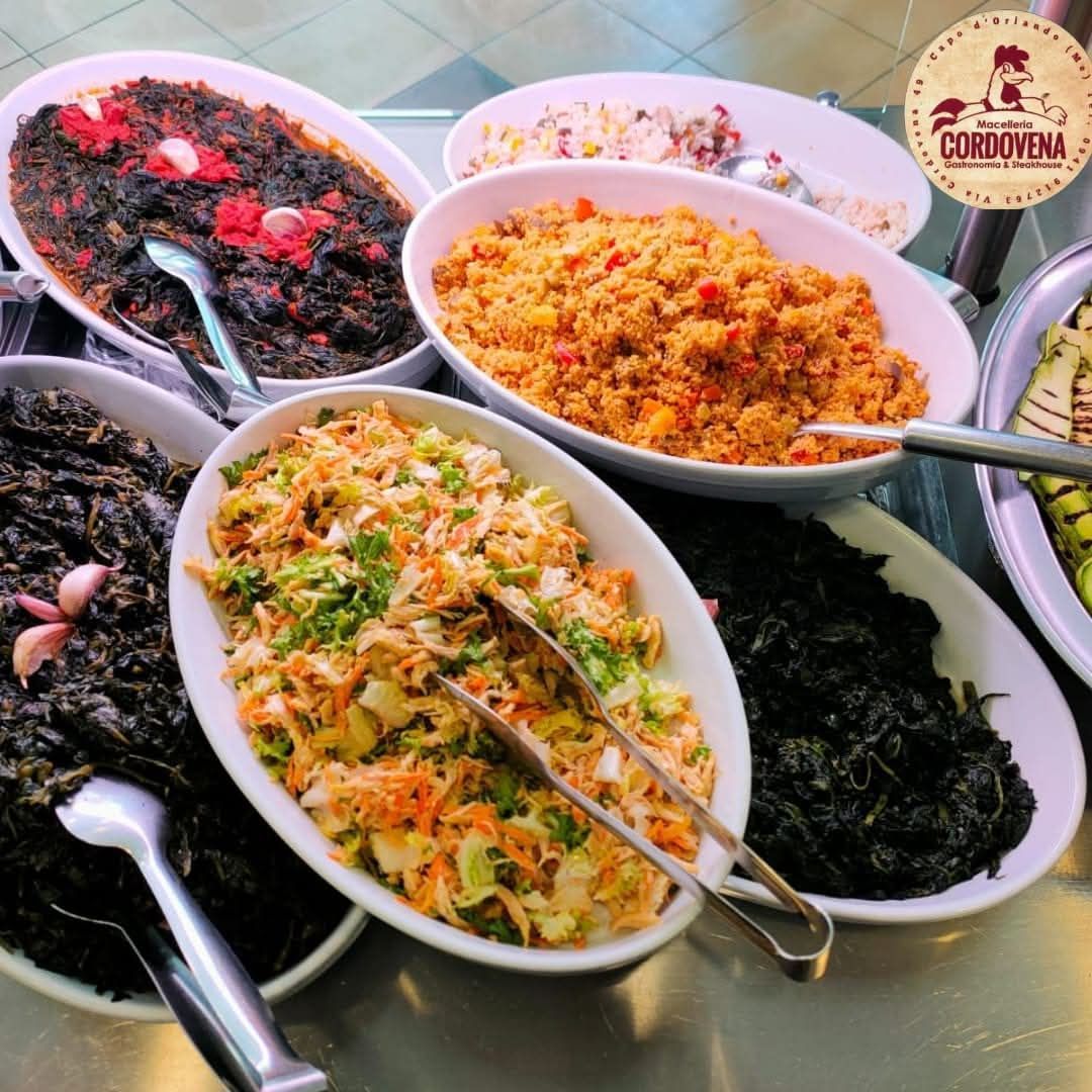 Buffet con vari piatti: insalate, riso e verdure, presentati in piatti da portata bianchi.