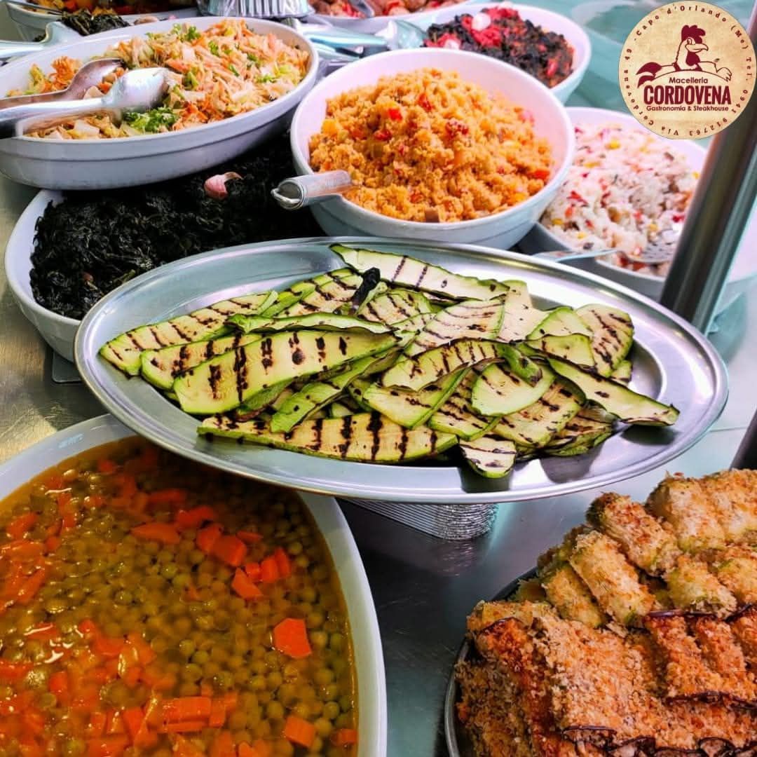 Vari piatti esposti: zucchine grigliate, couscous, piselli e altri cibi preparati.