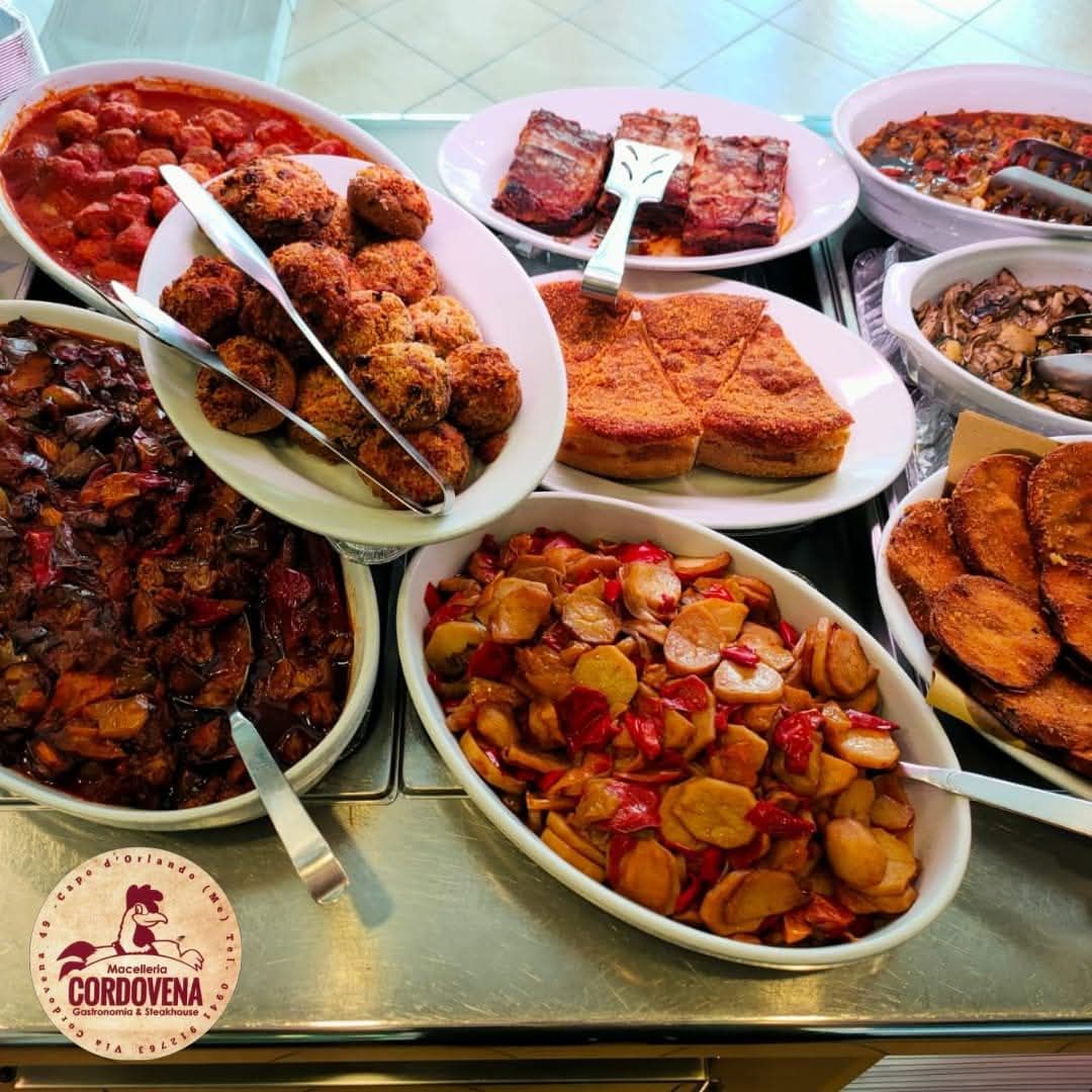 Un buffet di vari cibi cucinati in piatti da portata bianchi.