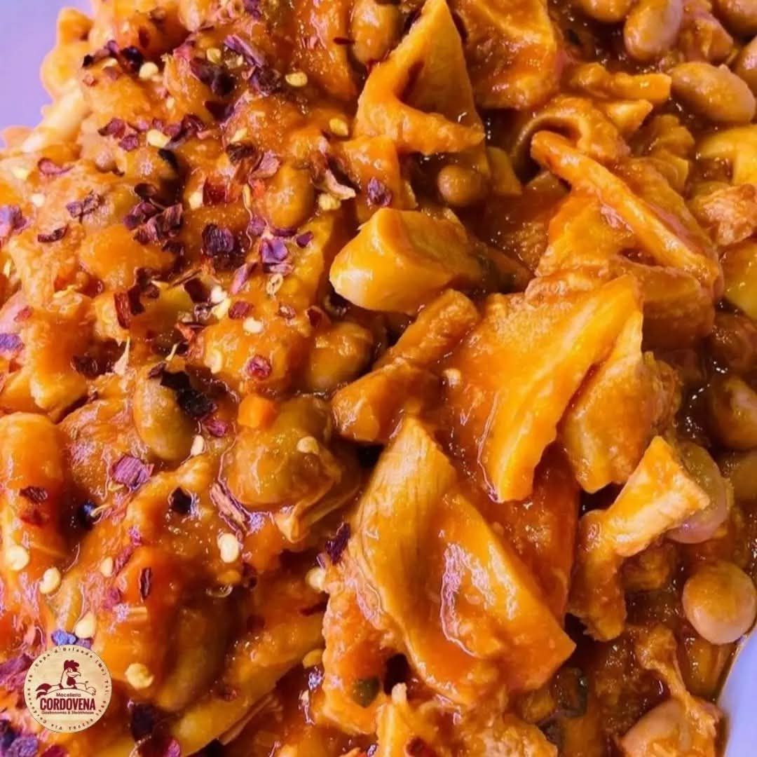 Primo piano di un piatto saporito con una ricca salsa all'arancia, fagioli visibili e fiocchi di peperoncino.