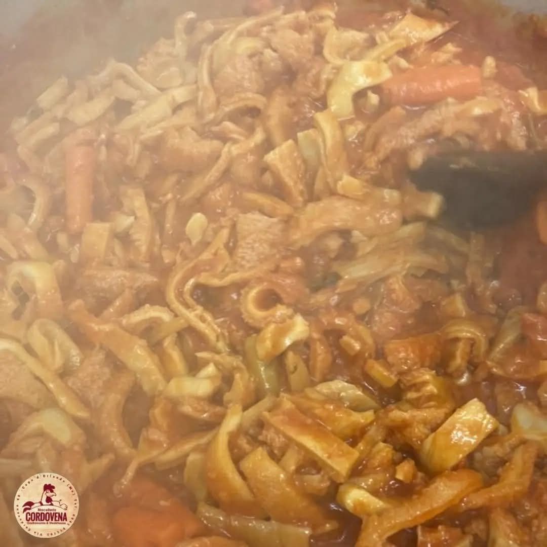 Primo piano di una pentola di pasta cotta con verdure in salsa rossa.