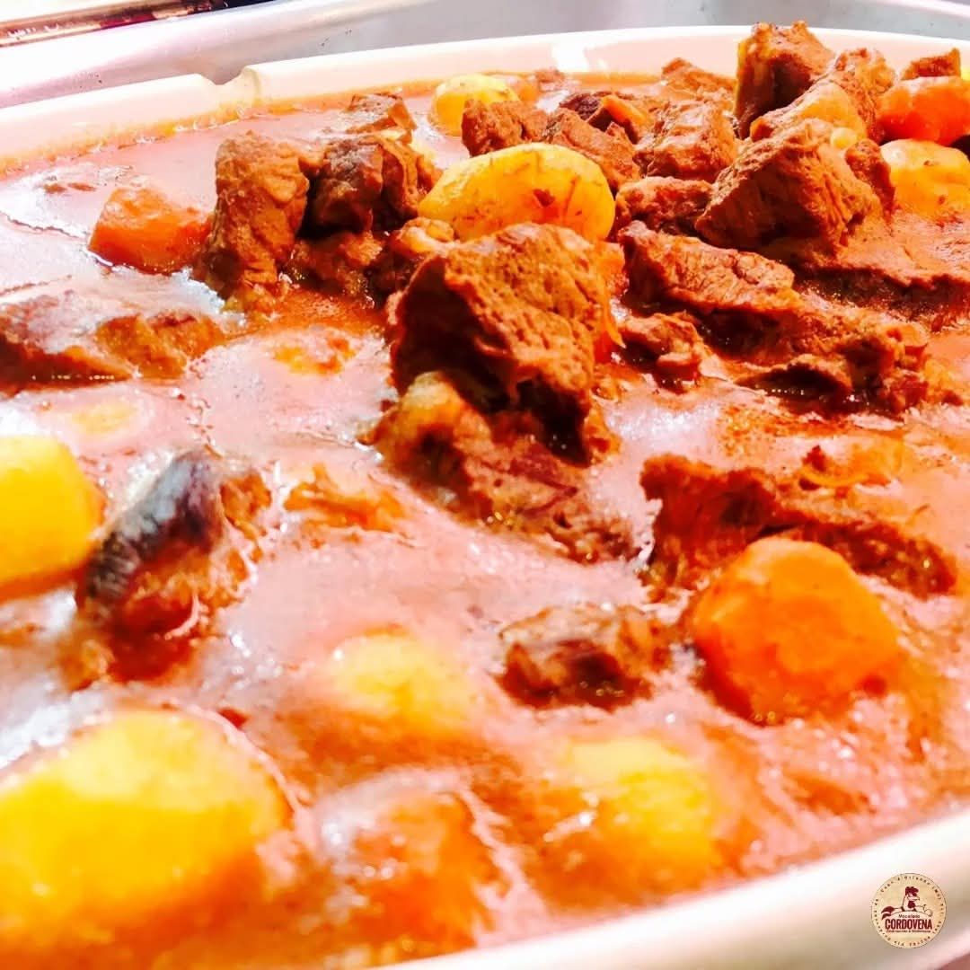 Spezzatino di manzo con patate e carote, in un piatto bianco.