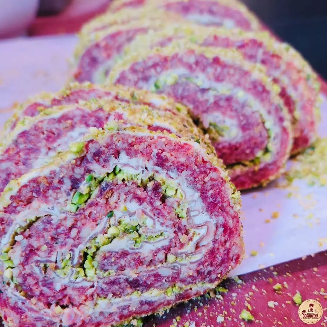 Rotolo di carne affettata con ripieno verde e giallo, impanato.