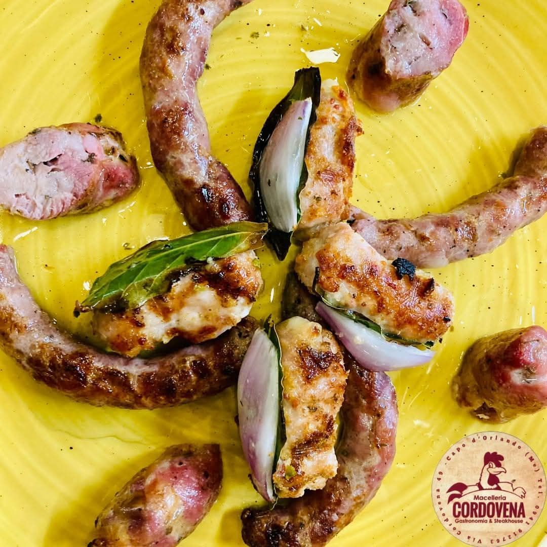 Salsiccia grigliata con cipolle tagliate a metà, alloro, su un piatto giallo.