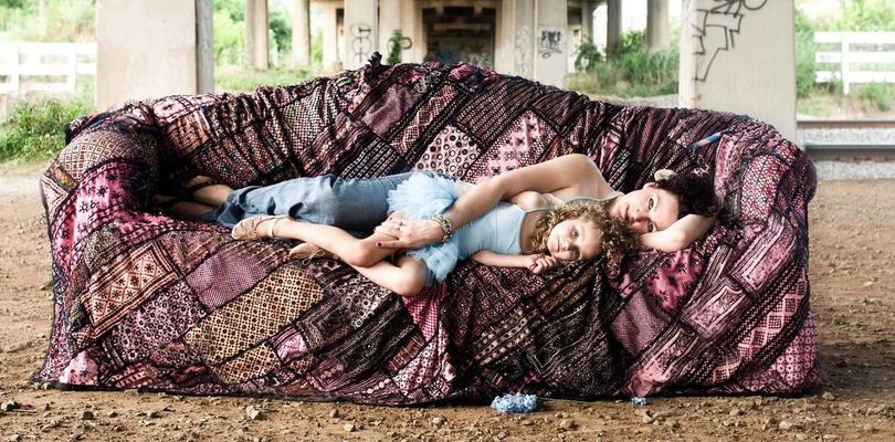 A woman and two children are laying on a couch