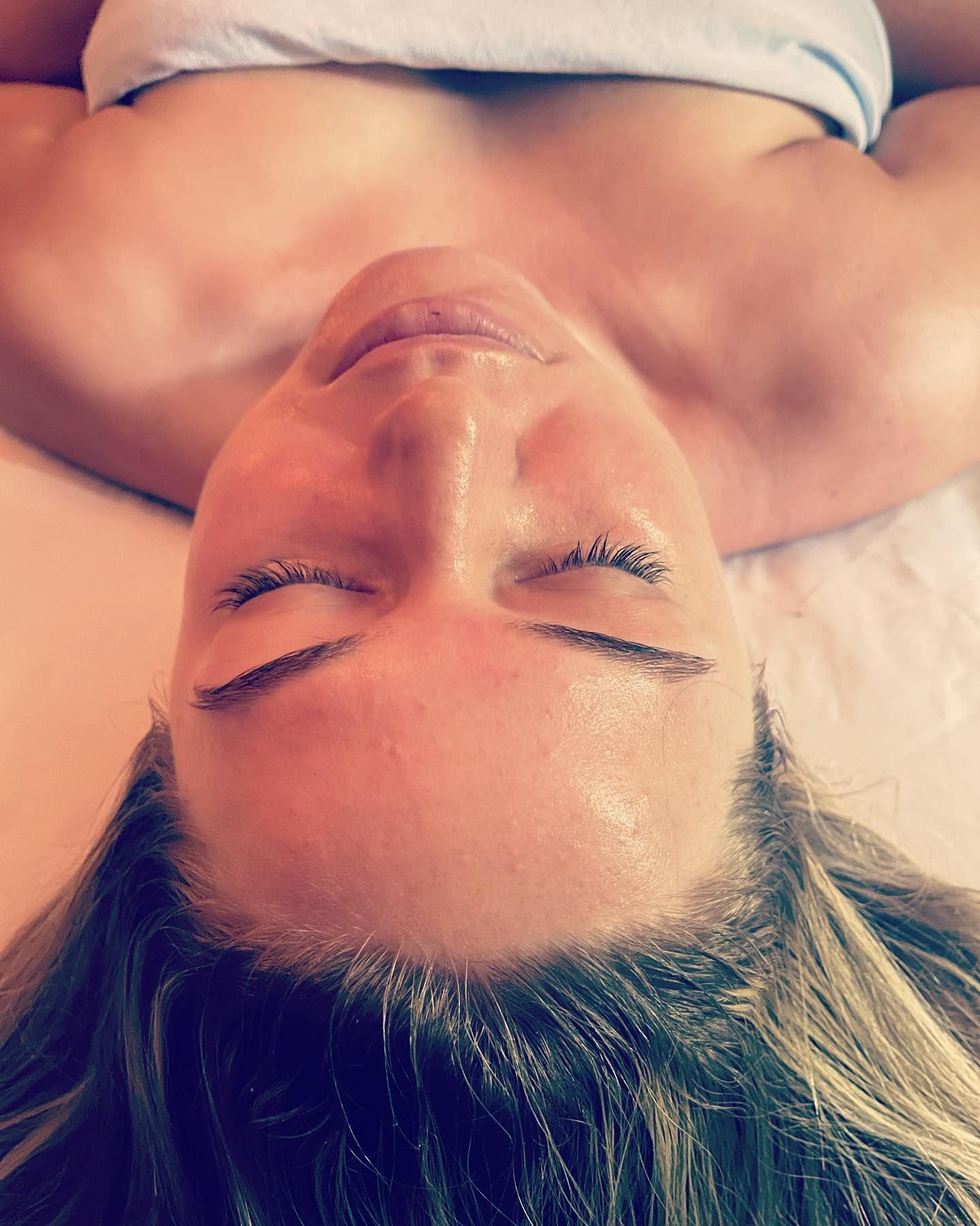 A woman is laying on her back with her eyes closed.