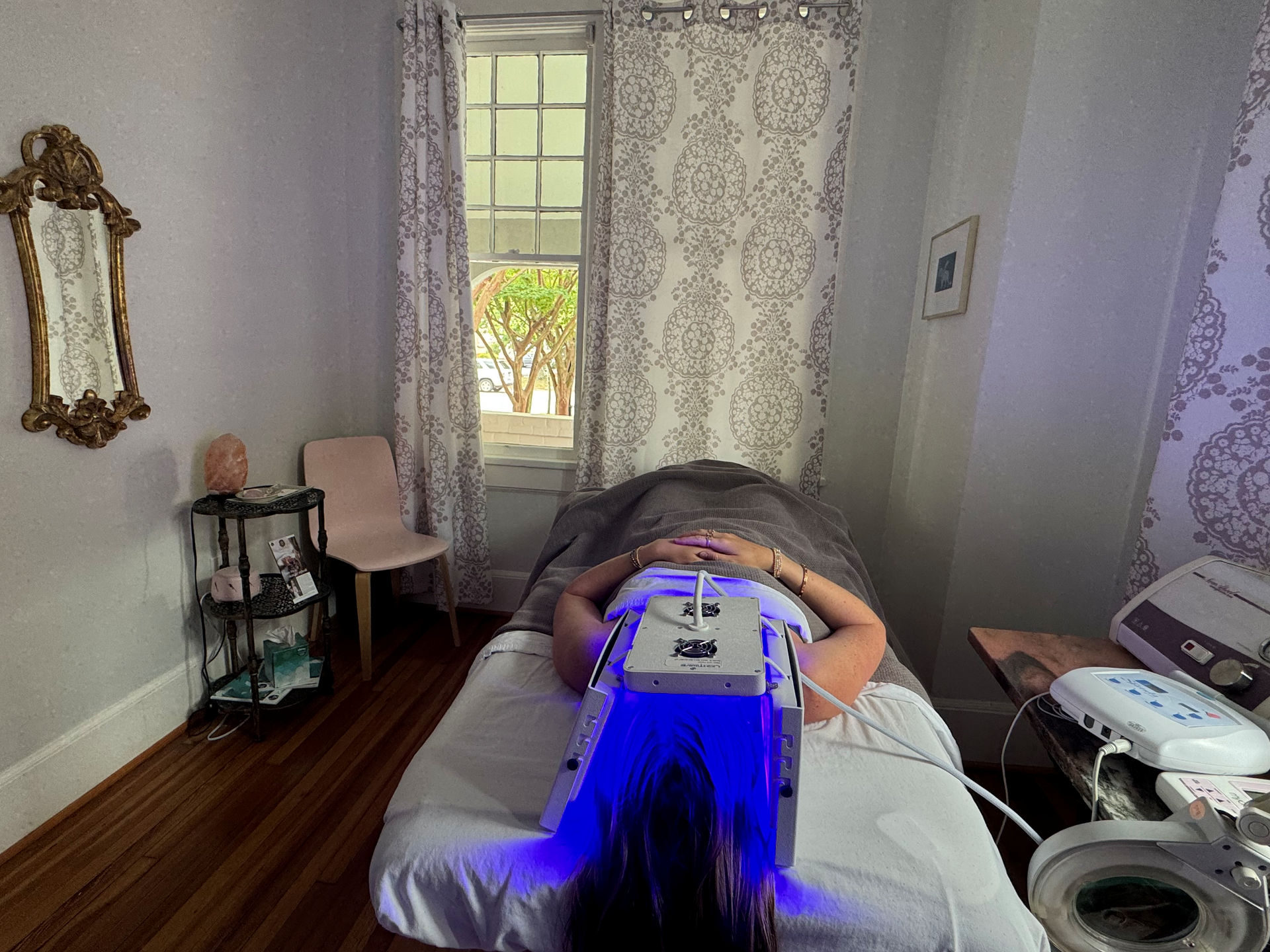 A woman is laying on a massage table in a room.