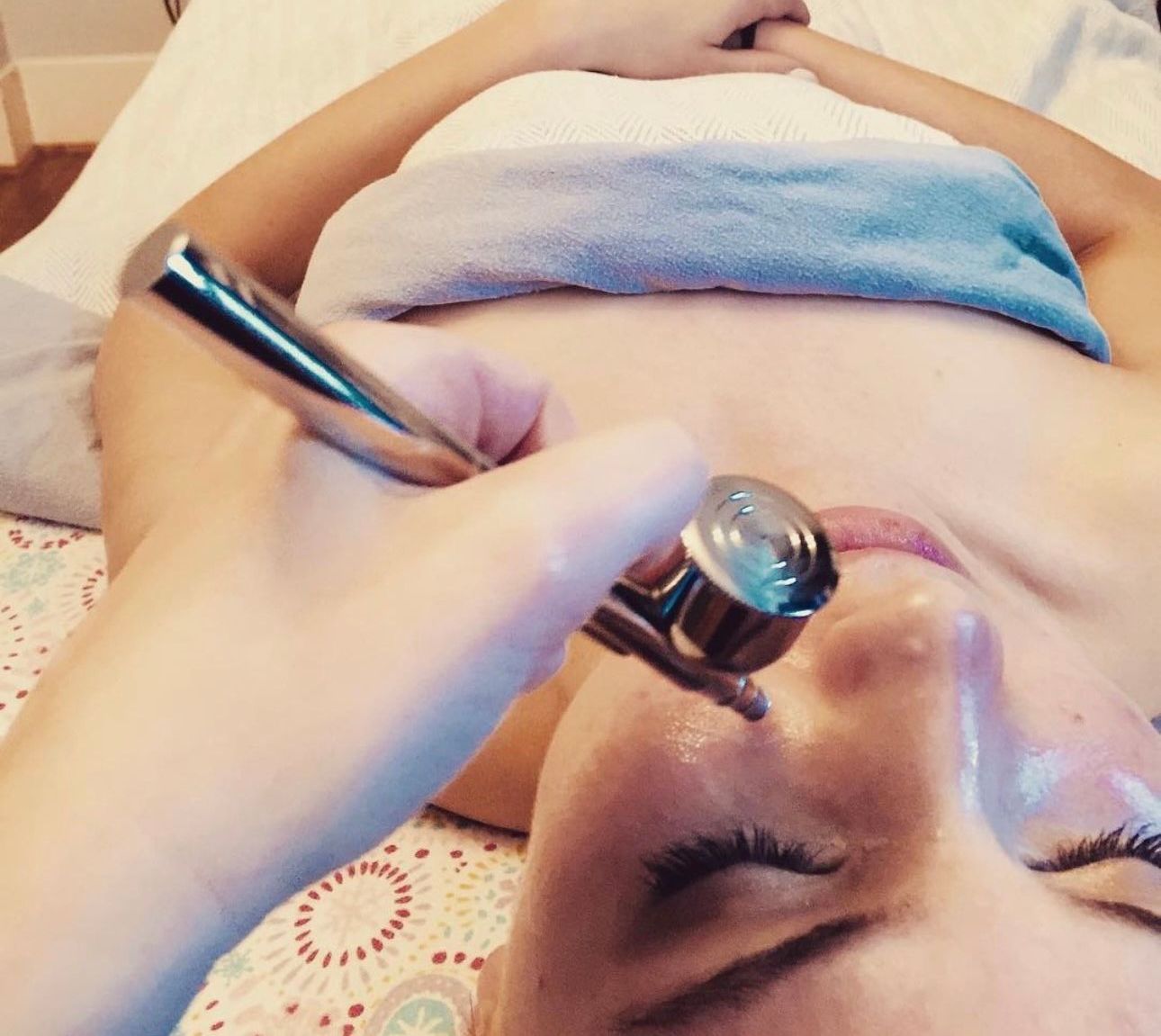 A woman is laying on a bed getting a facial treatment