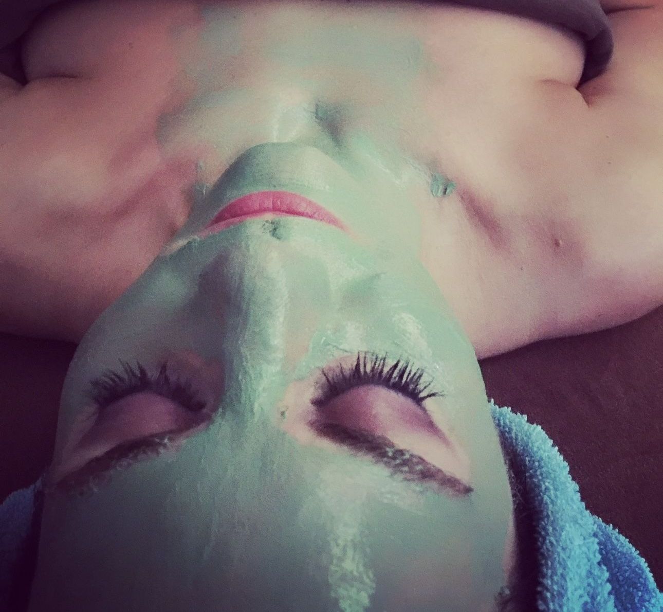 A woman is laying down with a green mask on her face