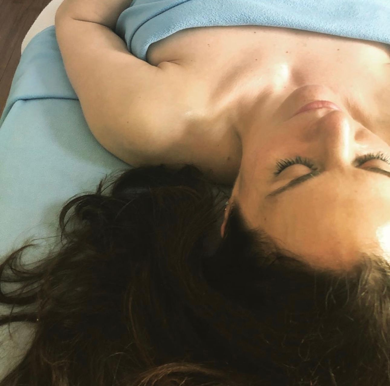 A woman is laying on a bed with her eyes closed