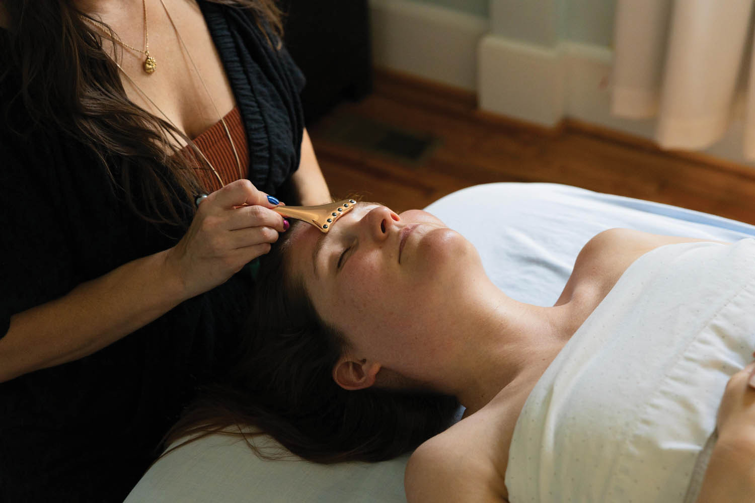 A woman is laying on a table getting a massage on her face.