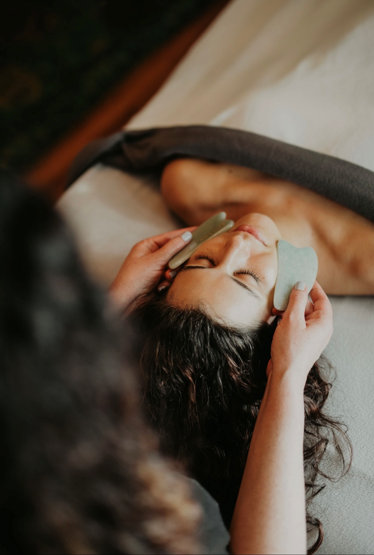 A woman is getting a gua sha treatment on her face.