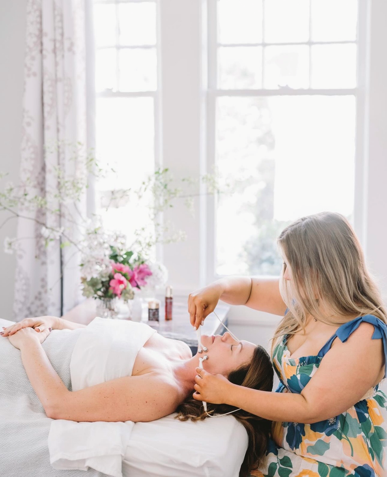 A woman is laying on a massage table getting a massage from another woman.