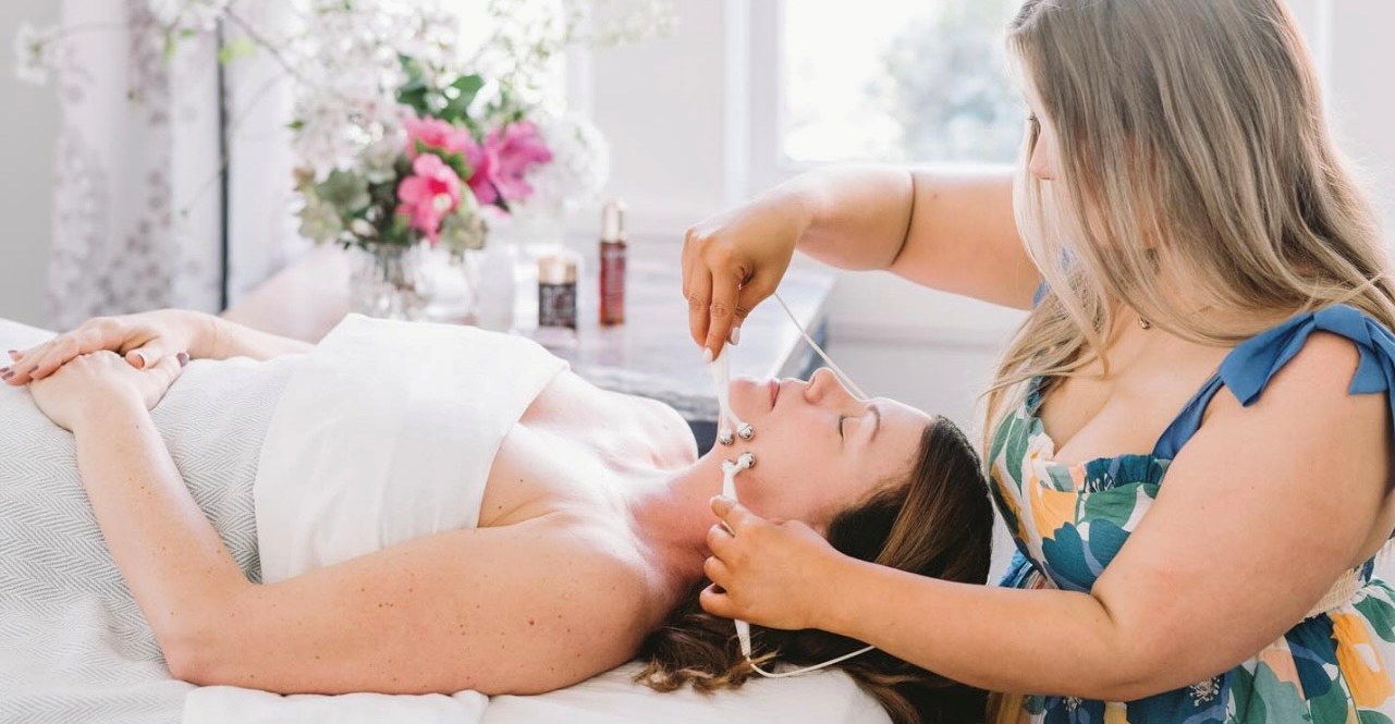 A woman is laying on a bed getting a massage from another woman.