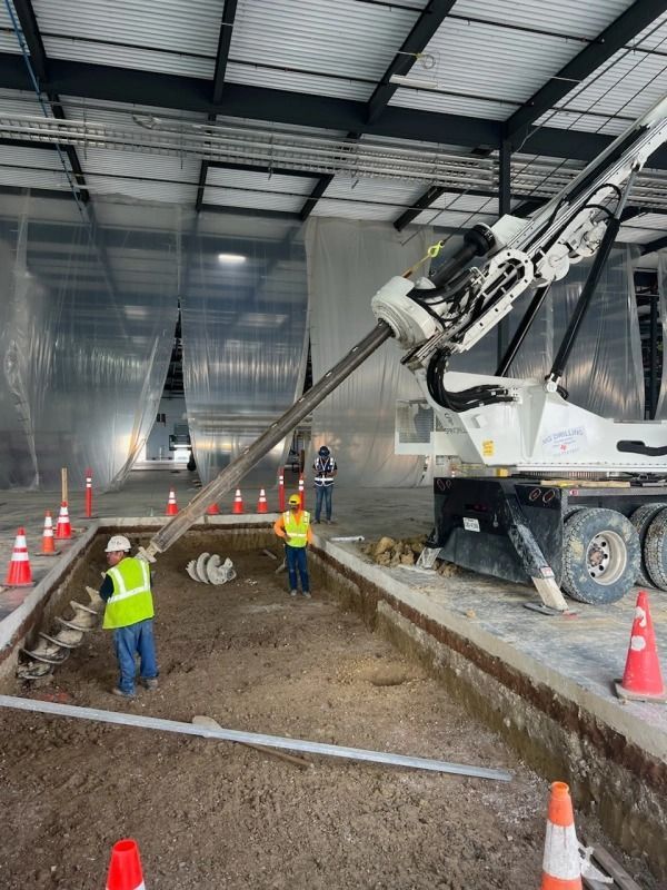 Concrete driveway being poured by a work crew next to a brown fence with a gate.