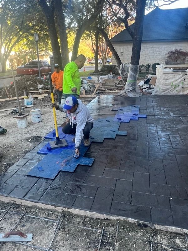 Workers stamping concrete patio with blue forms.
