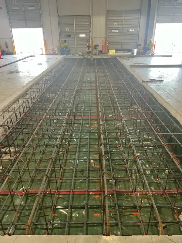 Wet concrete path with fence, under a covered area. Sign reads