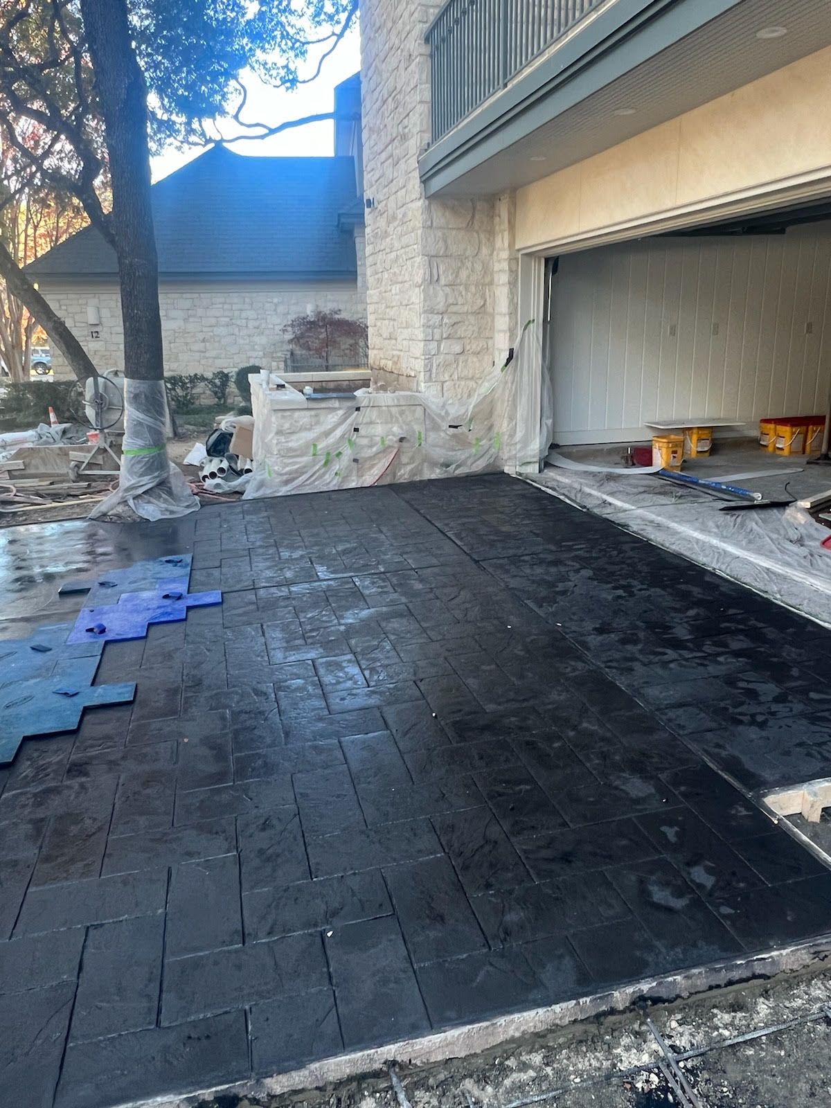 Newly paved dark driveway in front of a house, leading to an open garage.