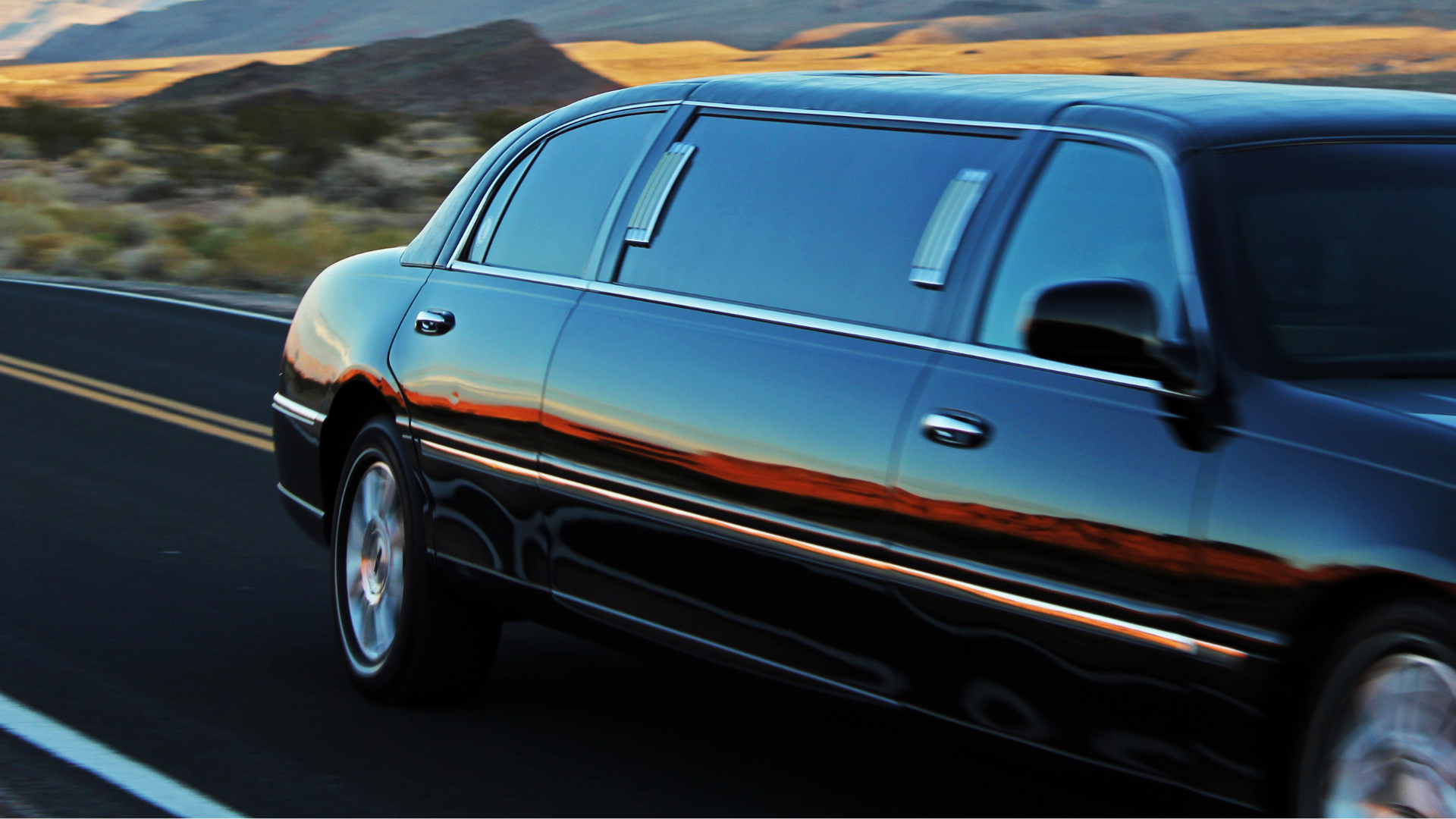 A man in a suit and tie is standing in front of a black car.