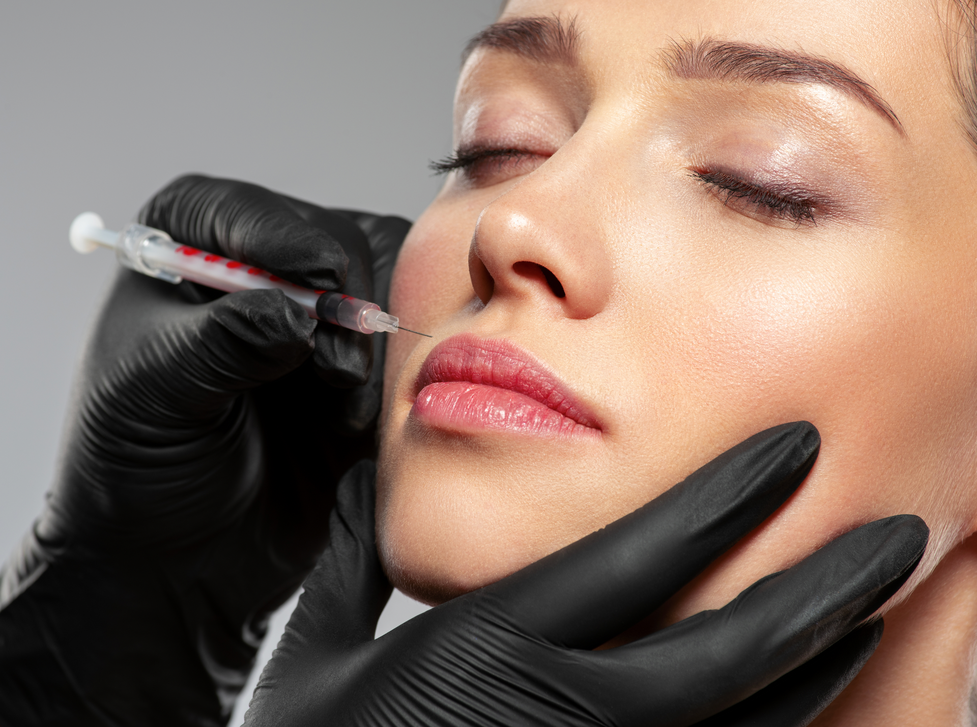 A woman is getting a botox injection in her lip.