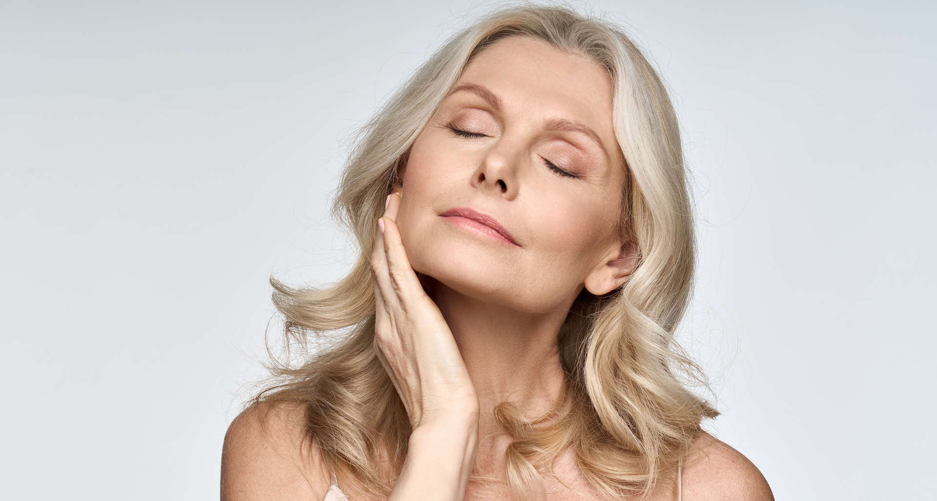 A woman is touching her face with her hand and her eyes closed.