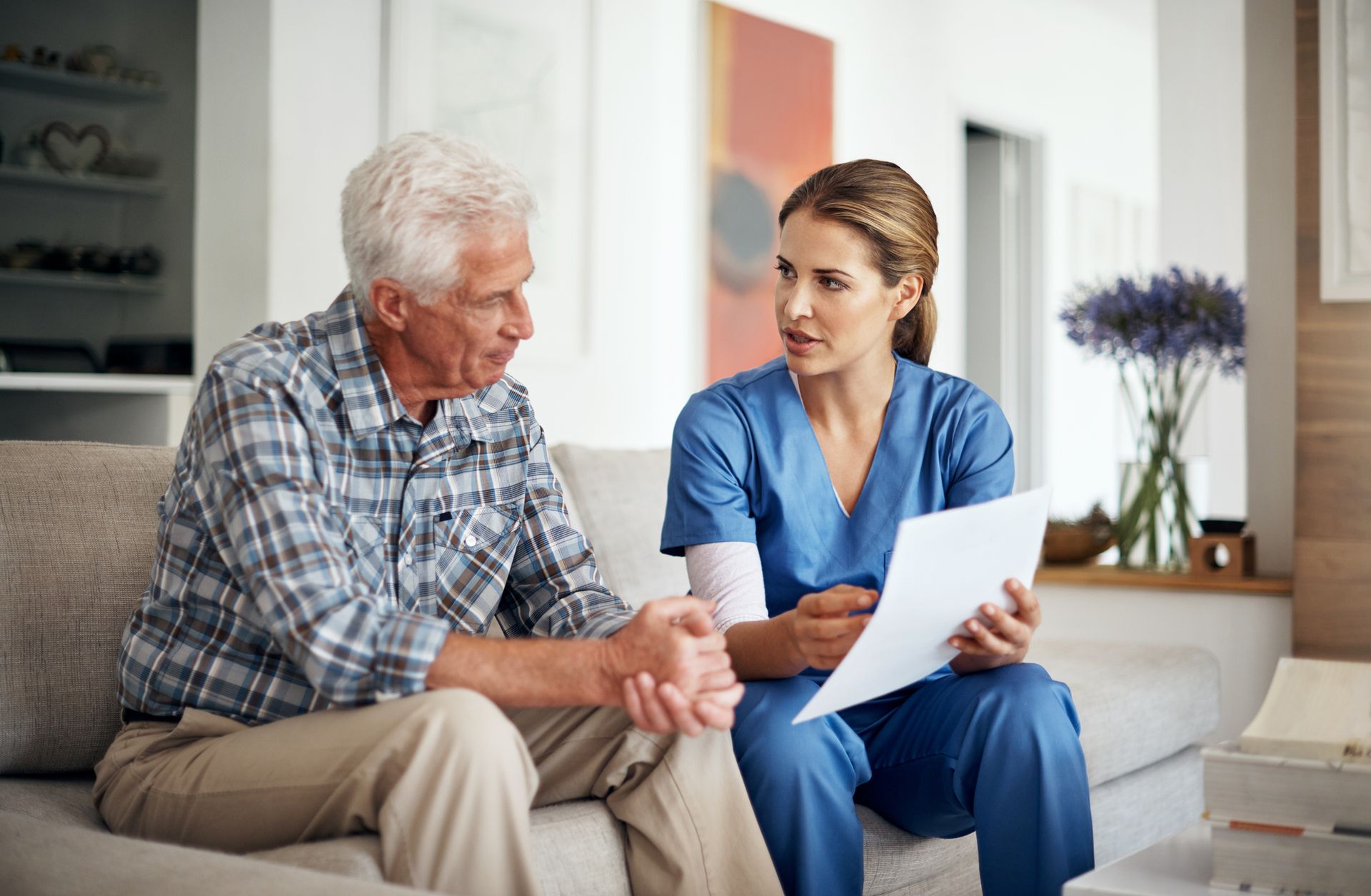 Shot of a female home health care worker discussing paperwork with her senior patient.