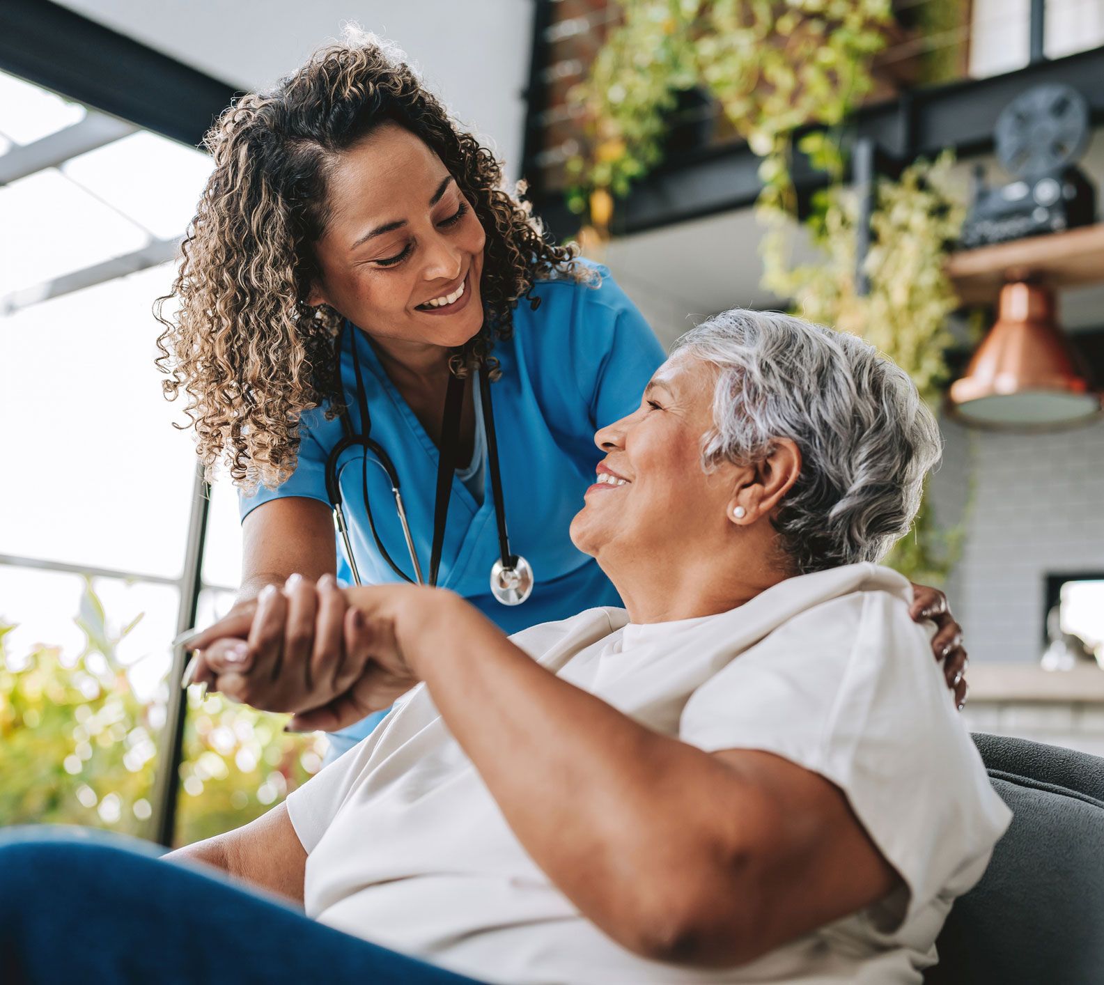 Nurse with a stethoscope helps a smiling elderly woman.