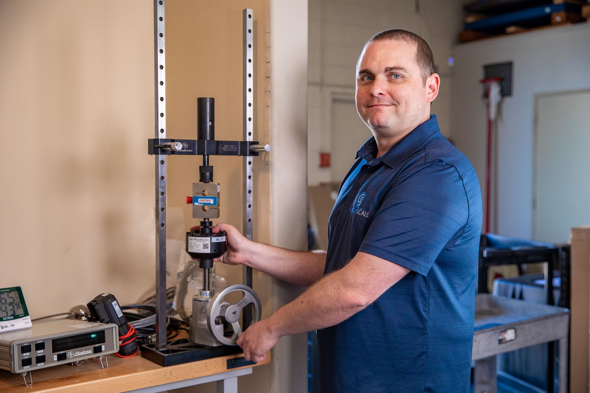 Man in blue shirt operating testing equipment; laboratory setting.