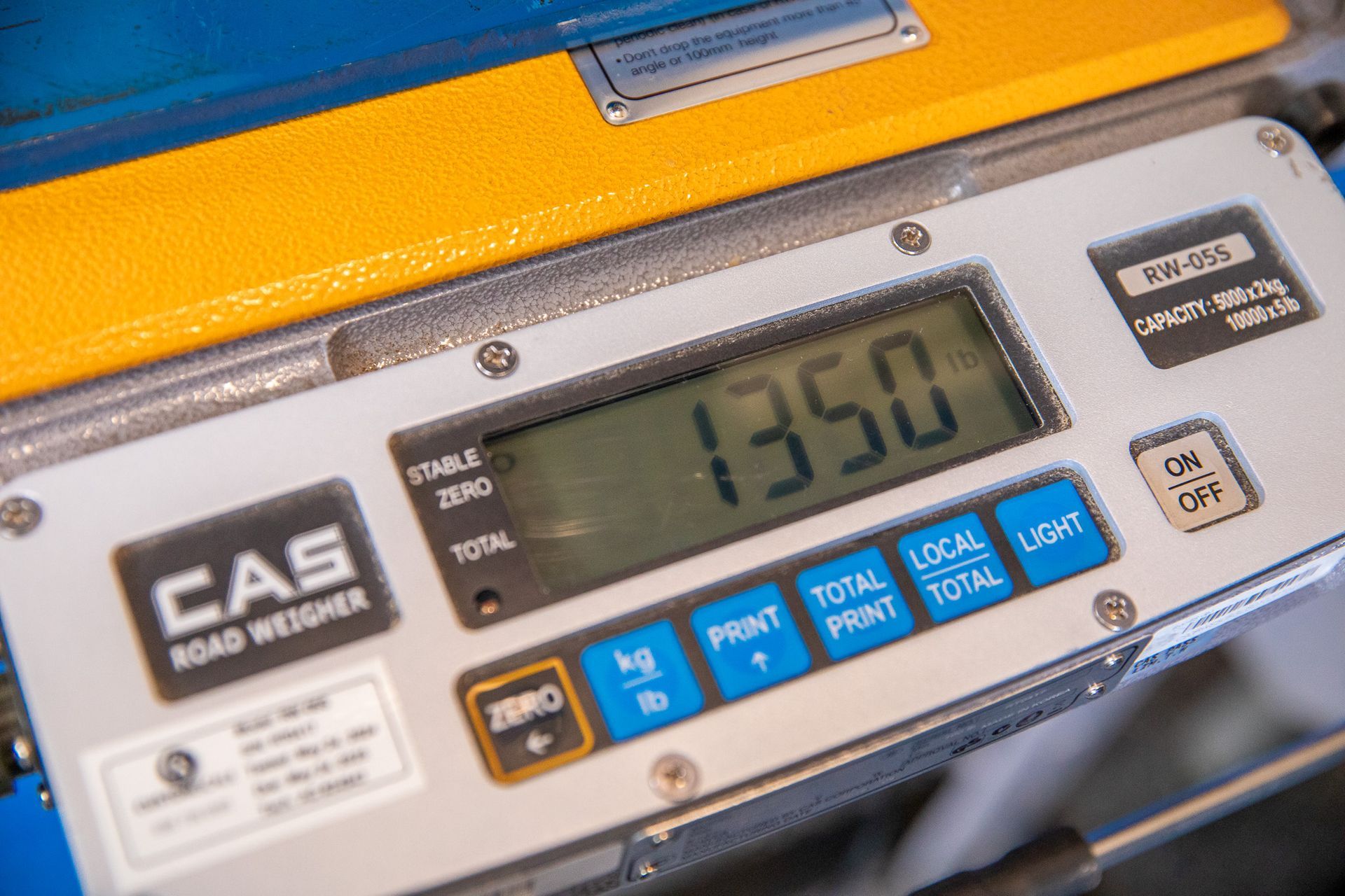 Man assembling machinery, in front of a metal frame on a wall.