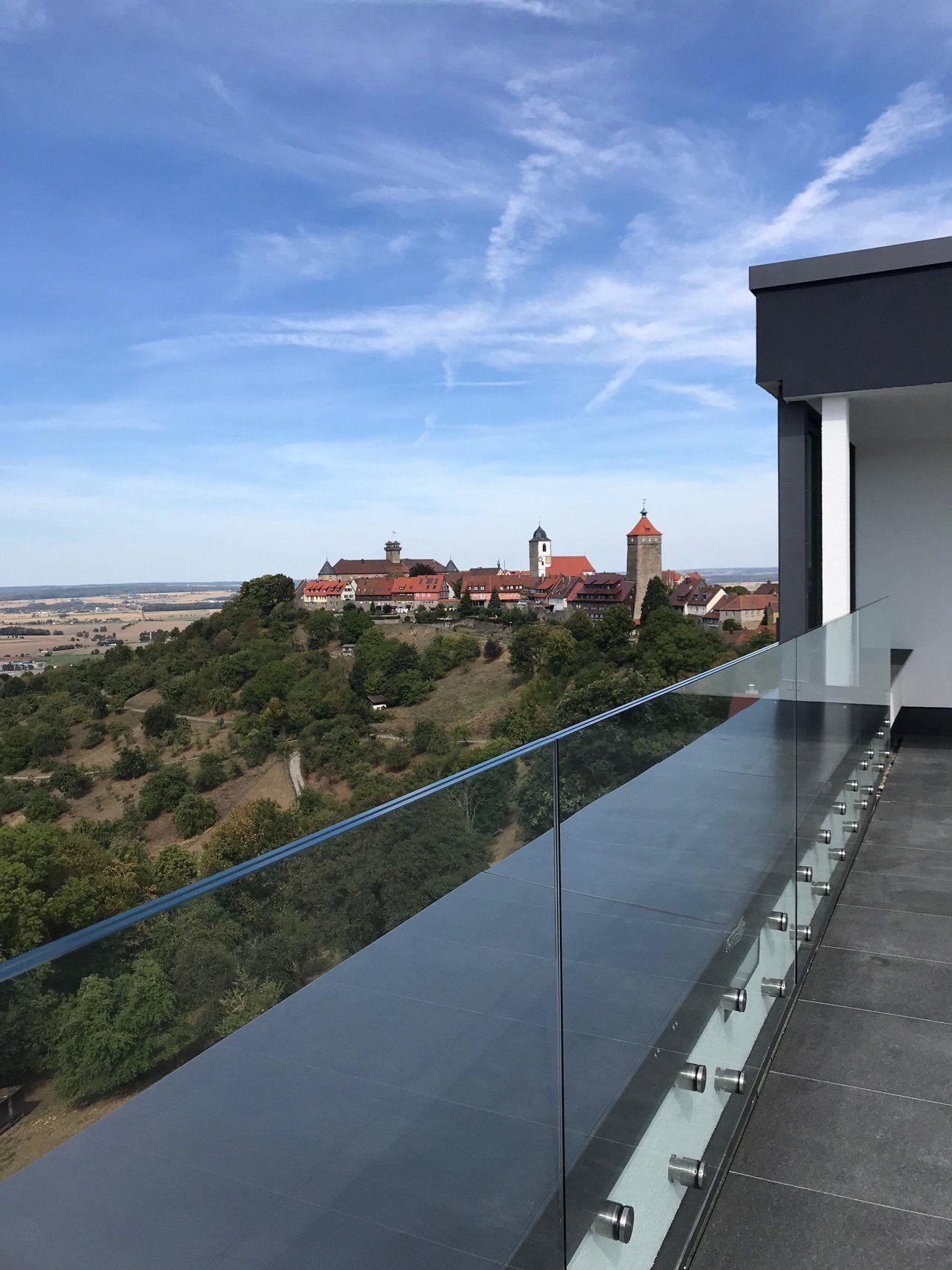 Ein Blick auf eine Stadt von einem Balkon mit Glasgeländer.