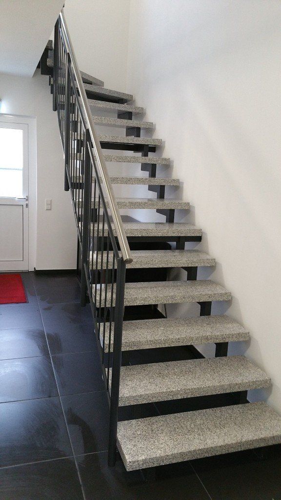 Eine Treppe mit Granitstufen und einem Metallgeländer in einem Flur.