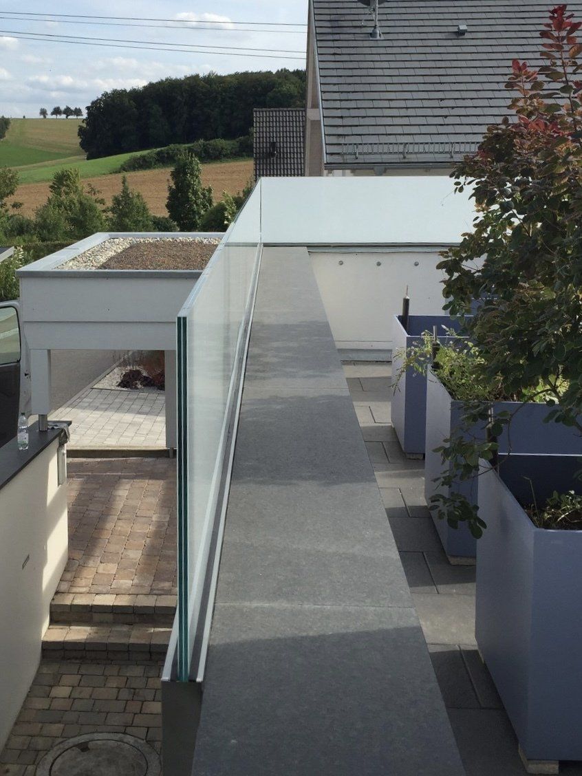 Ein Gehweg mit einem Glasgeländer, der zu einem Haus führt