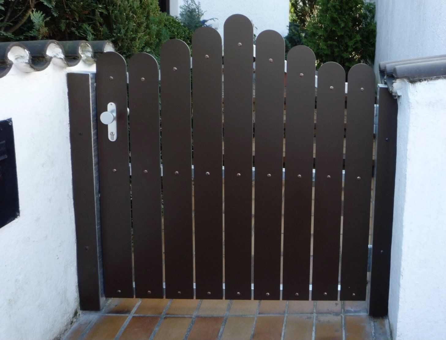 Ein brauner Holzzaun mit einem Briefkasten im Hintergrund