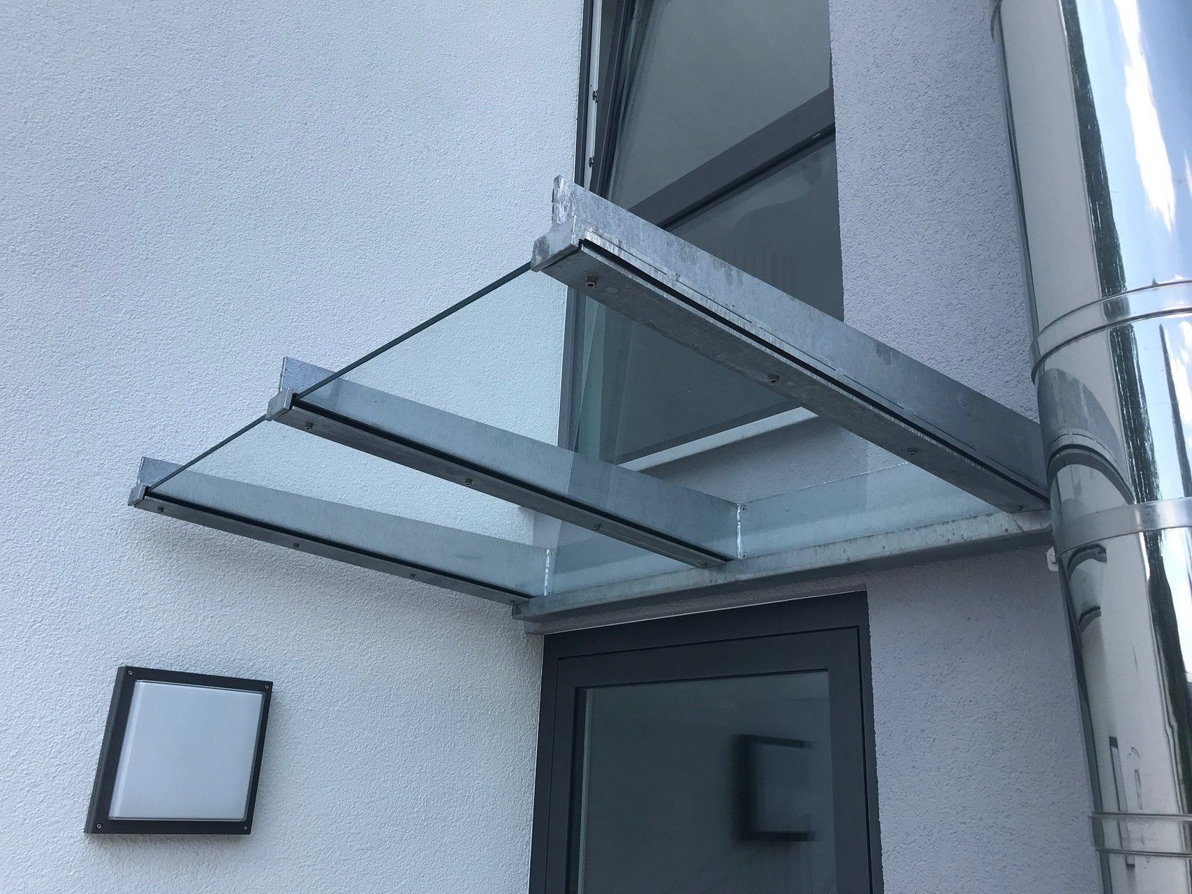 Ein Glasdach über einer Tür an der Seite eines Gebäudes.