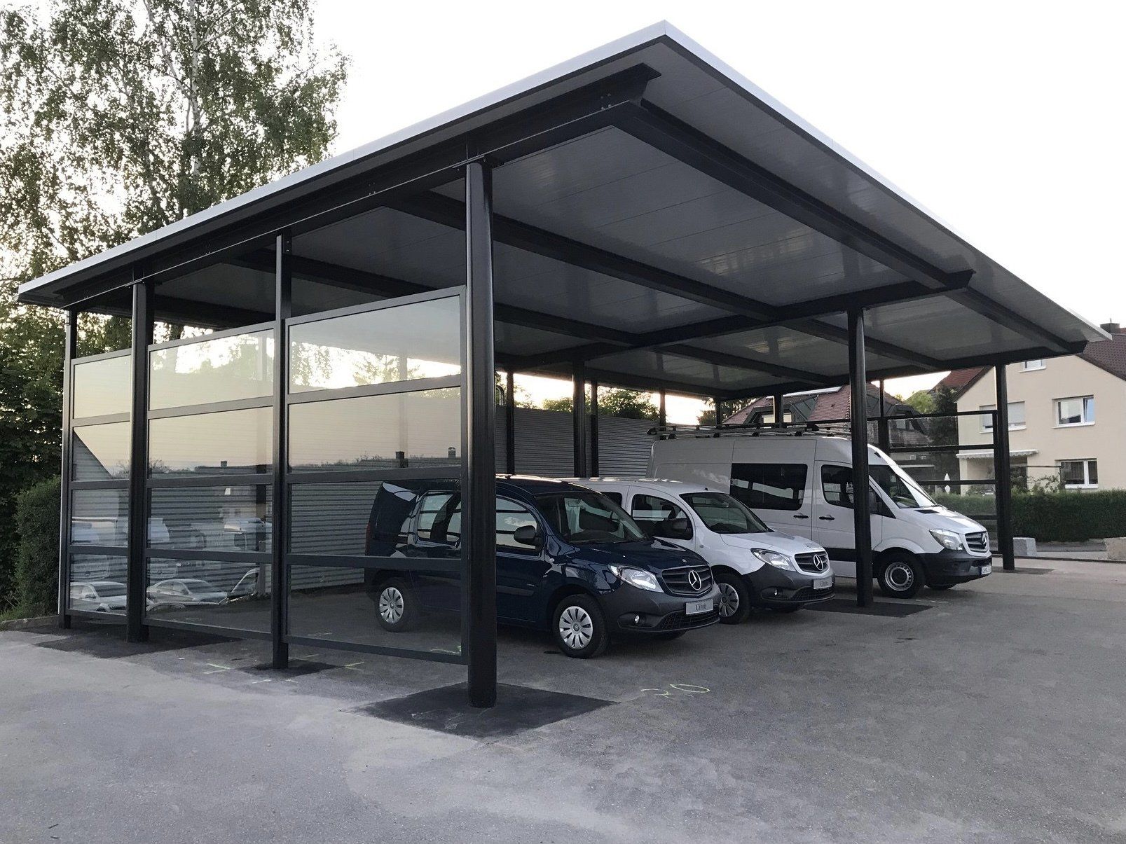 Unter einem Carport ist eine Reihe von Autos geparkt.
