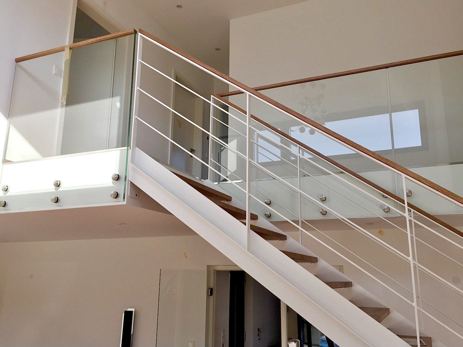 Eine weiße Treppe mit einem Glasgeländer in einem Haus