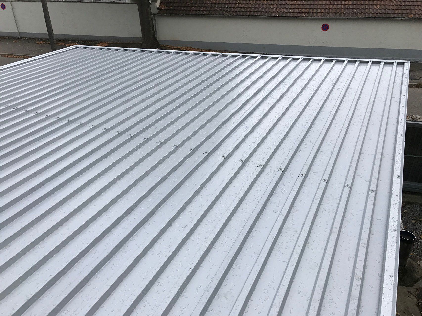 Auf einem Gebäude befindet sich ein weißes Metalldach.