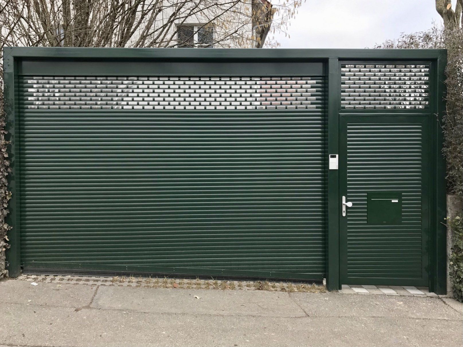 Ein grünes Garagentor mit einem Tor und einem Briefkasten.