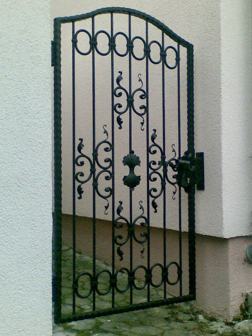 Ein schmiedeeisernes Tor steht vor einer weißen Wand