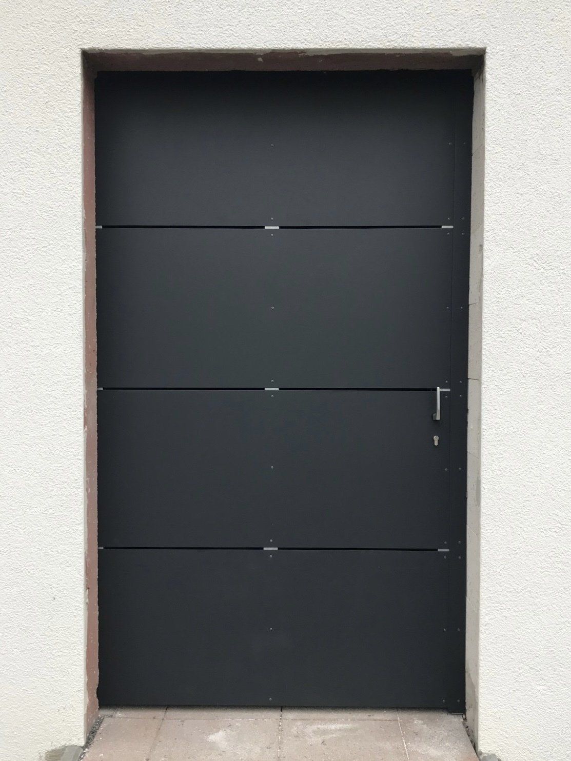 Eine schwarze Tür steht an einer weißen Wand.