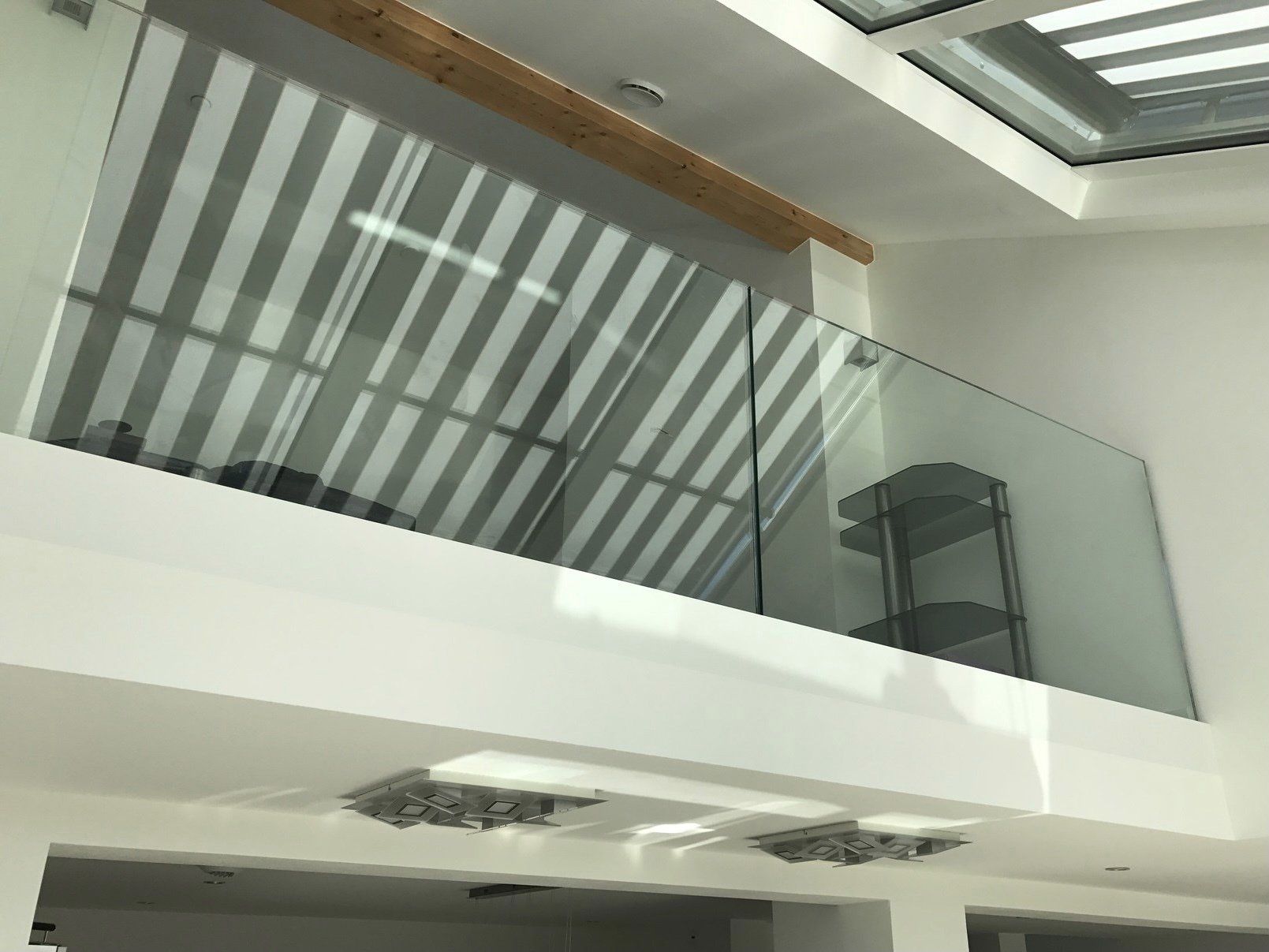 Ein Balkon mit einem Glasgeländer zwischen zwei Stockwerken in einem Gebäude.