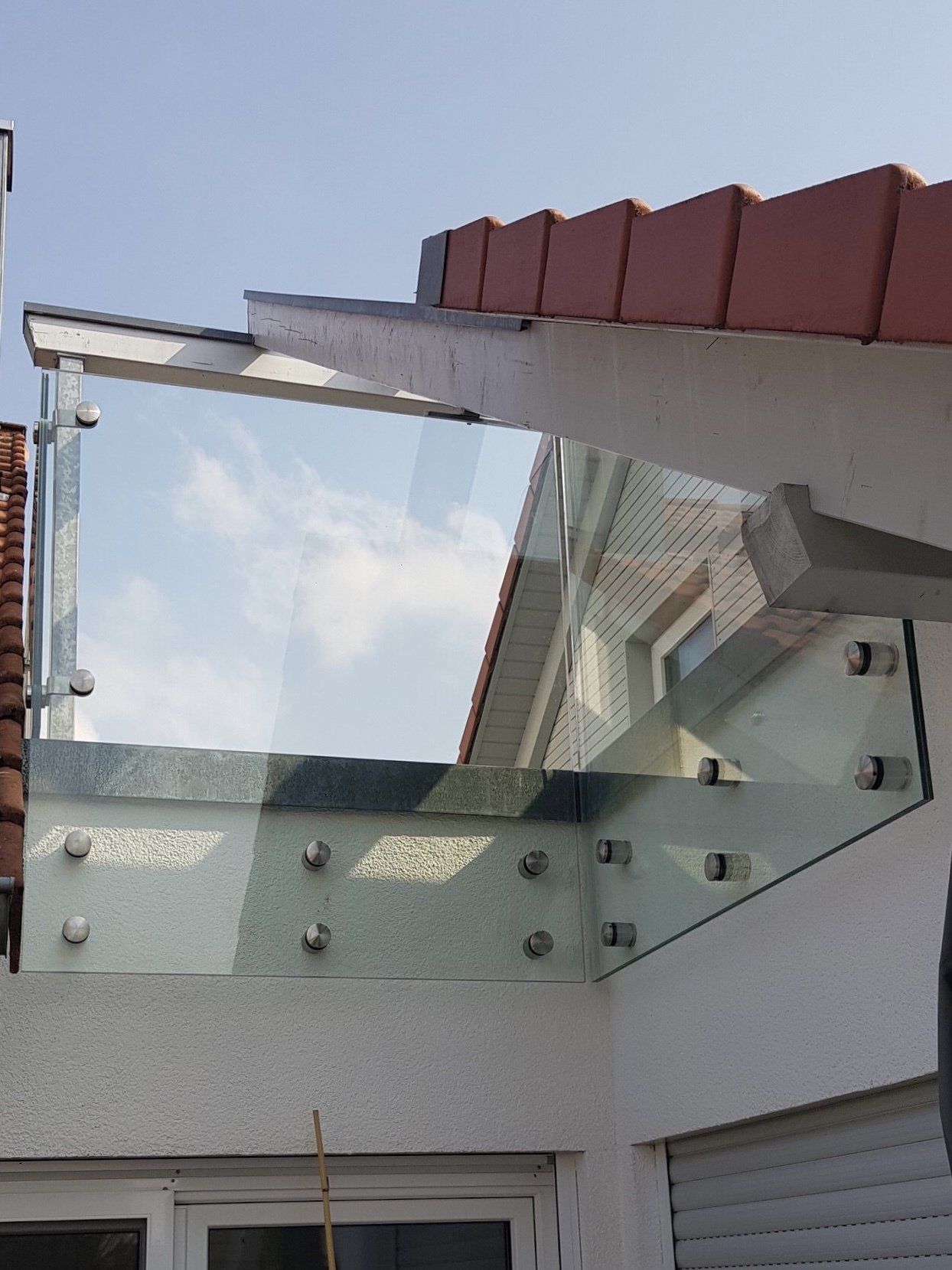 Ein Balkon mit einem Glasgeländer und einem Vordach darüber