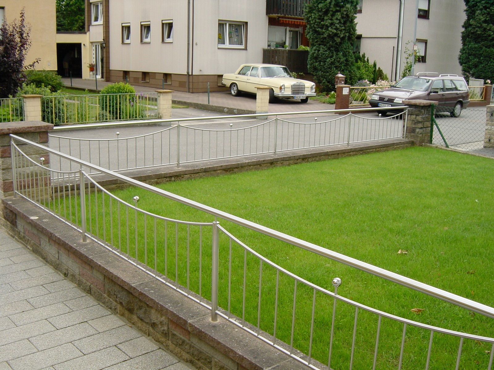 Ein Edelstahlzaun umgibt einen üppigen grünen Hof